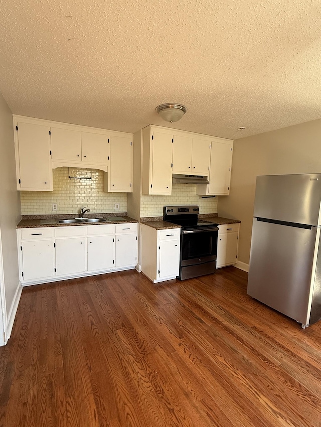 kitchen featuring under cabinet range hood, dark countertops, white cabinetry, appliances with stainless steel finishes, and dark wood-style flooring