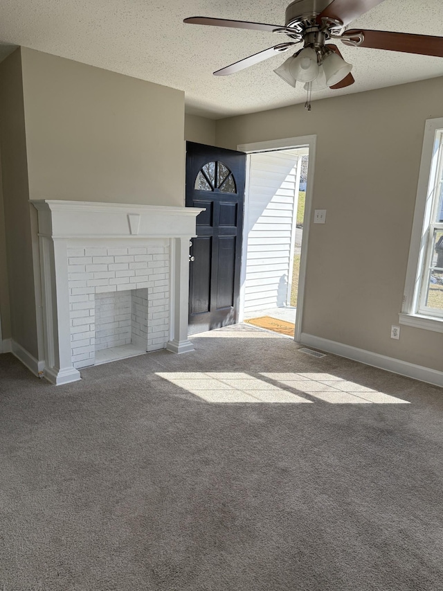 unfurnished living room with carpet floors, plenty of natural light, a brick fireplace, and a textured ceiling