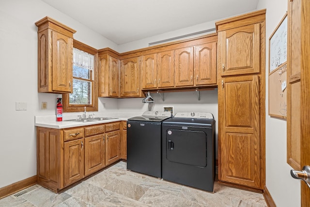 washroom featuring a sink, visible vents, baseboards, washer and dryer, and cabinet space