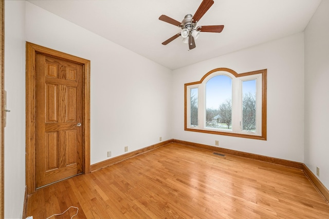 unfurnished room with light wood finished floors, baseboards, visible vents, and ceiling fan