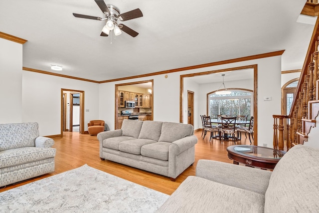 living area with light wood-style flooring, stairs, ornamental molding, and baseboards