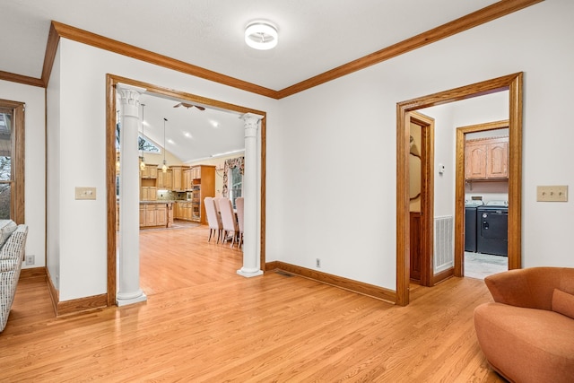 interior space featuring washing machine and dryer, baseboards, ornamental molding, light wood-type flooring, and decorative columns