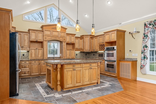kitchen featuring decorative backsplash, appliances with stainless steel finishes, dark wood-style flooring, dark stone countertops, and a center island