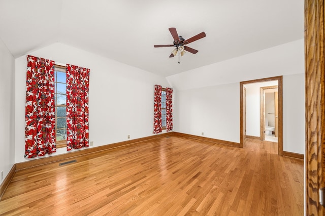 spare room with vaulted ceiling, baseboards, visible vents, and light wood-style floors