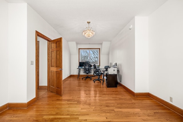 office area with a chandelier, baseboards, and light wood finished floors