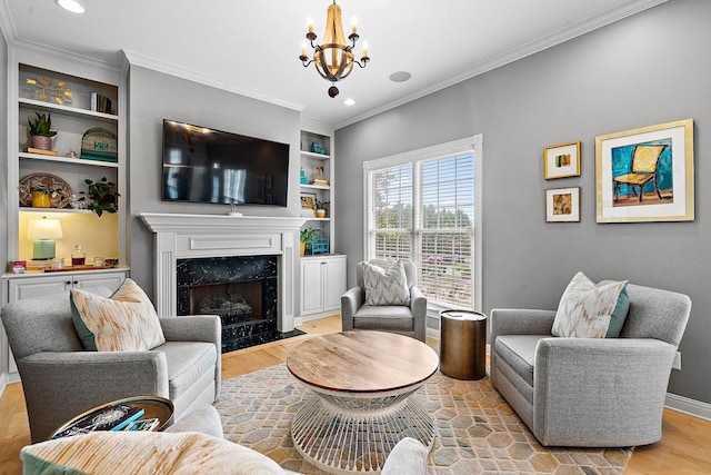 living room featuring a notable chandelier, a fireplace, wood finished floors, built in features, and crown molding