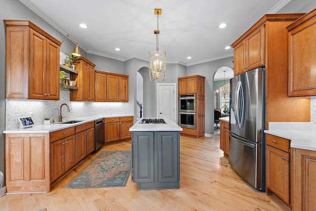 kitchen featuring arched walkways, a chandelier, a sink, appliances with stainless steel finishes, and brown cabinetry