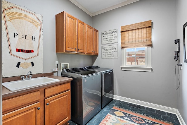 washroom featuring cabinet space, baseboards, ornamental molding, washing machine and dryer, and a sink