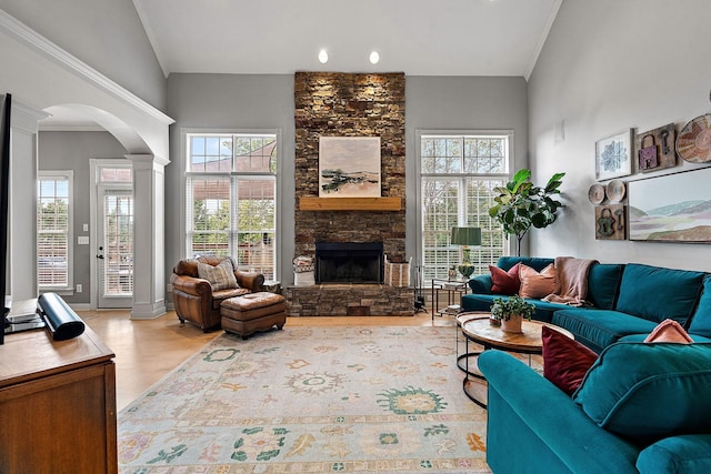 living room featuring light wood-type flooring, a healthy amount of sunlight, a fireplace, and arched walkways