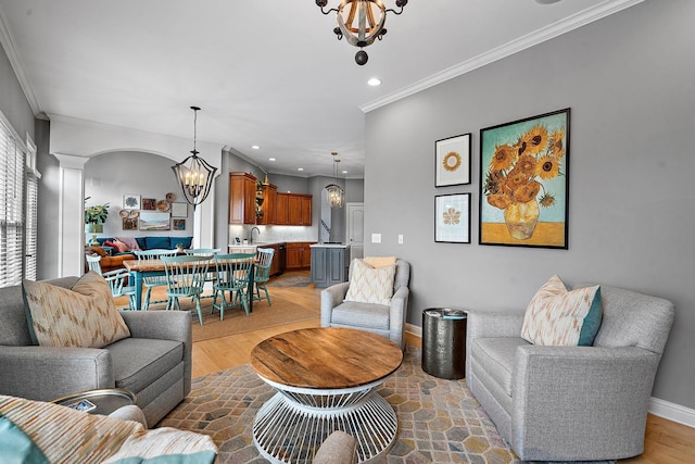 living area featuring baseboards, crown molding, ornate columns, a notable chandelier, and recessed lighting