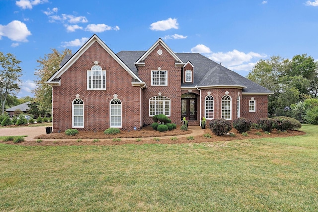 view of front of house featuring brick siding, a front lawn, and roof with shingles