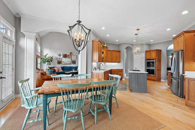 dining space with light wood-type flooring, arched walkways, a chandelier, and recessed lighting