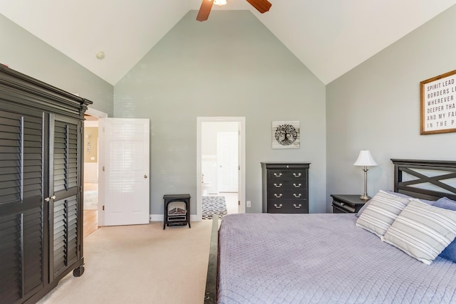 carpeted bedroom featuring ceiling fan, high vaulted ceiling, ensuite bathroom, baseboards, and a wood stove