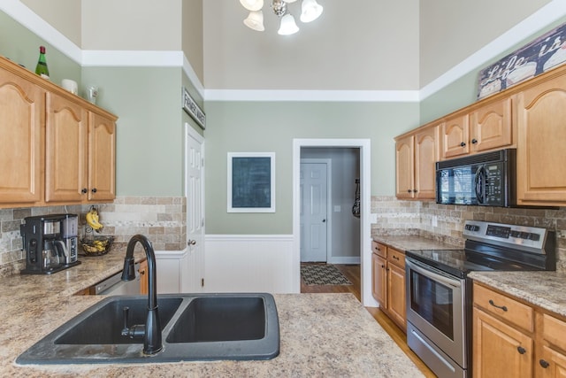 kitchen with electric stove, a towering ceiling, decorative backsplash, a sink, and black microwave