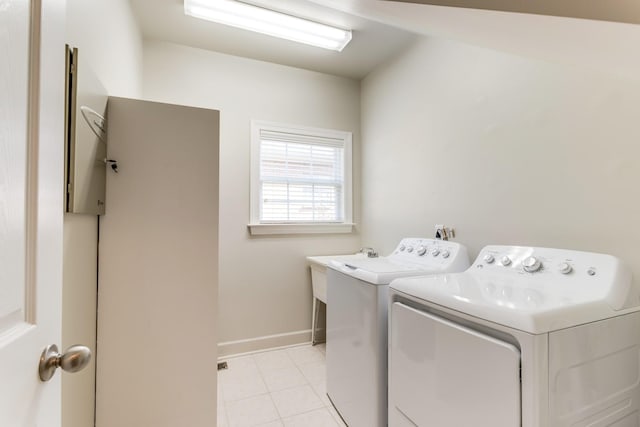 laundry area with laundry area, washing machine and dryer, light tile patterned floors, and baseboards