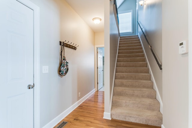 stairs with wood finished floors, visible vents, and baseboards