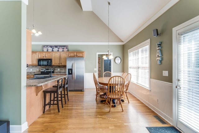 dining space featuring an inviting chandelier, light wood-style flooring, visible vents, and a wainscoted wall