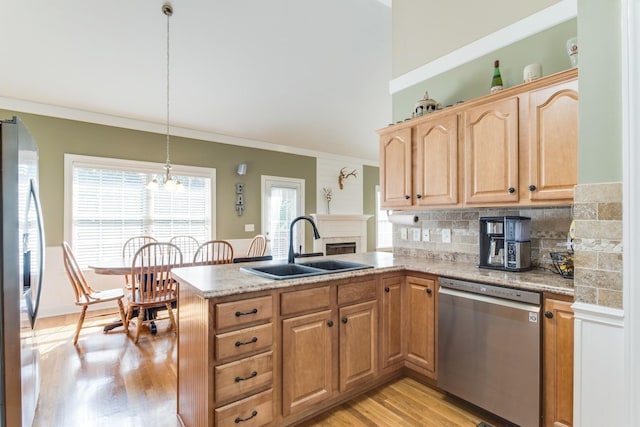 kitchen featuring light wood-style flooring, ornamental molding, a peninsula, stainless steel appliances, and a sink