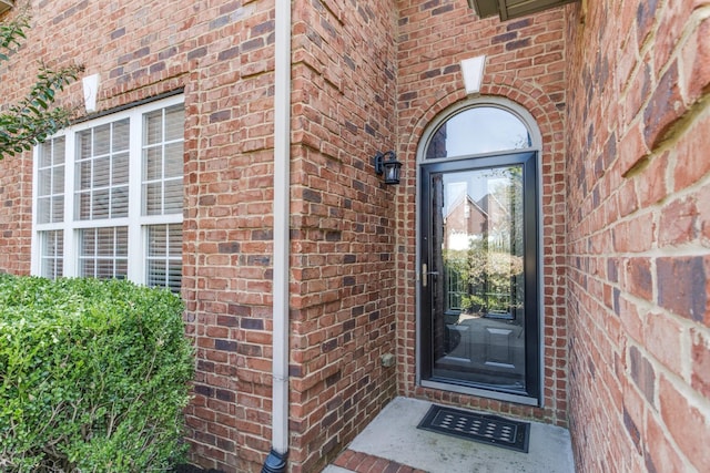 view of exterior entry featuring brick siding