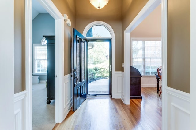 foyer with a wainscoted wall, a decorative wall, and wood finished floors