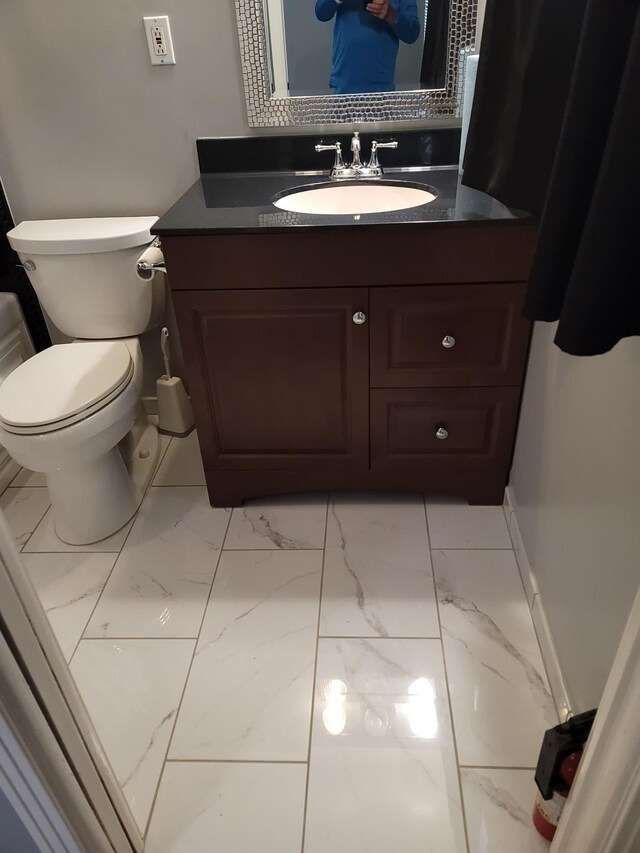 bathroom featuring toilet, marble finish floor, and vanity