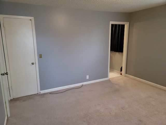 empty room with carpet floors, baseboards, and a textured ceiling