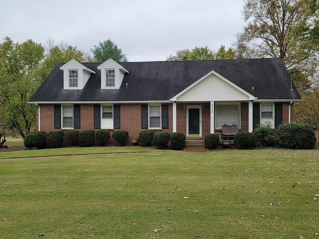 view of front of home with a porch, brick siding, and a front lawn