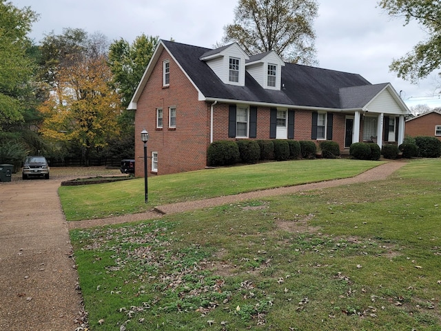 cape cod house with brick siding and a front yard