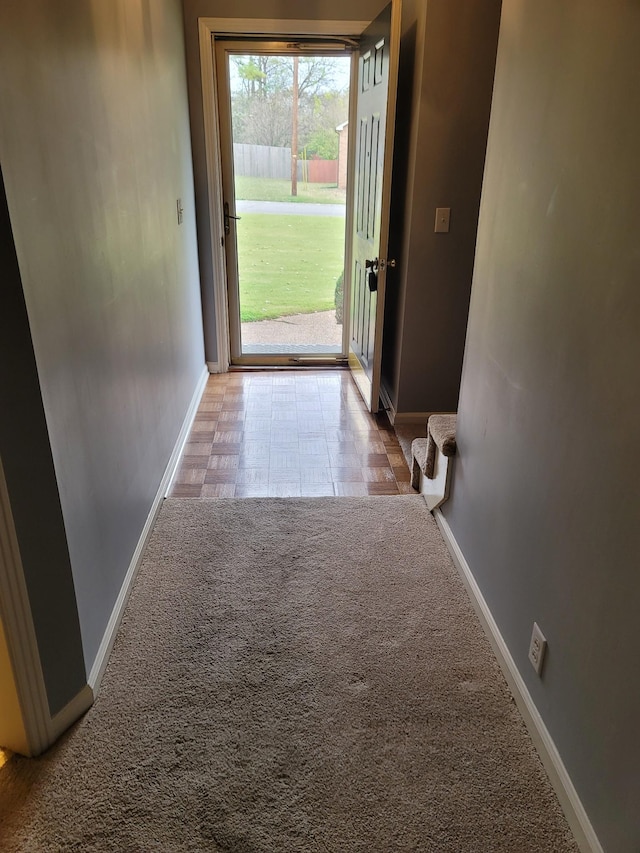 doorway with carpet floors and baseboards