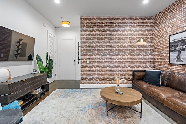 living room with recessed lighting, baseboards, brick wall, and wood finished floors