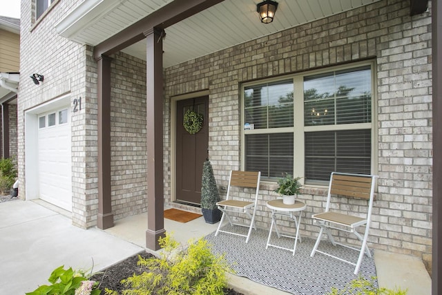 view of exterior entry with a garage, covered porch, and brick siding