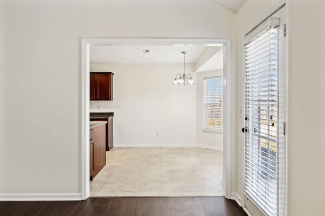 interior space featuring baseboards, lofted ceiling, decorative light fixtures, light wood-style floors, and a chandelier