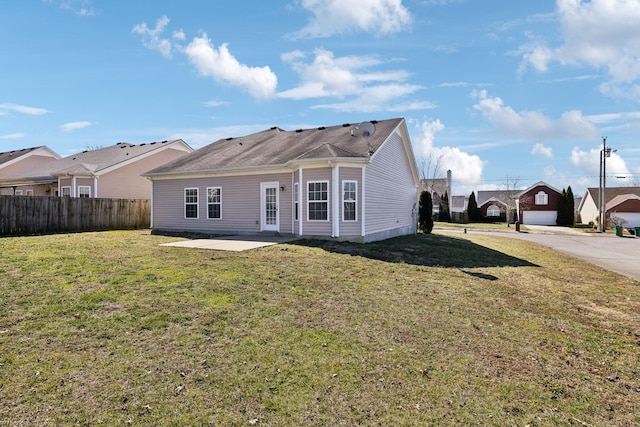 back of house featuring a yard, a residential view, fence, and a patio