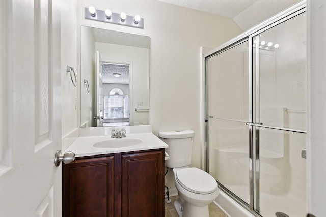 bathroom featuring a textured ceiling, vanity, a shower stall, and toilet