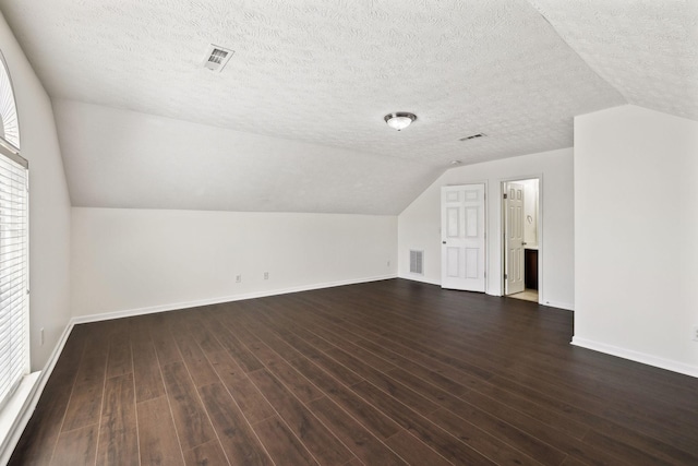 bonus room featuring dark wood-style floors, a textured ceiling, visible vents, and baseboards