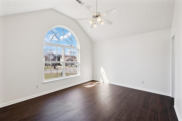 spare room with ceiling fan, visible vents, baseboards, vaulted ceiling, and dark wood finished floors