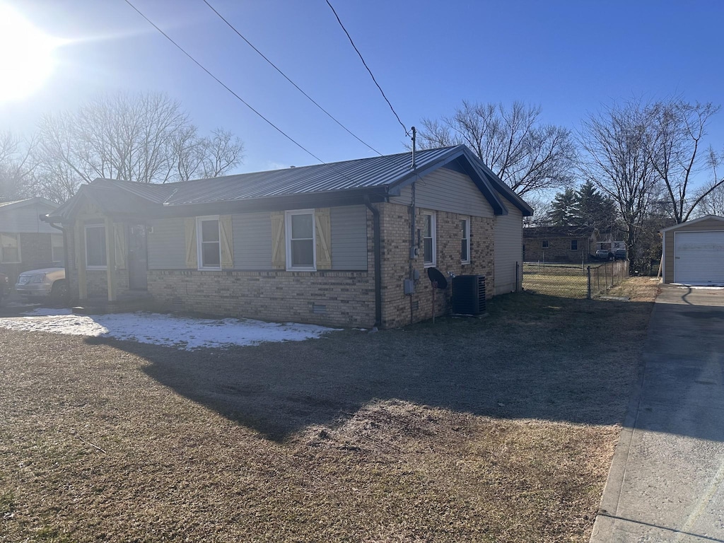 view of property exterior with cooling unit, brick siding, metal roof, and an outbuilding