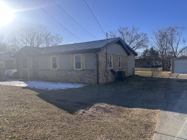 view of property exterior with cooling unit, brick siding, metal roof, and an outbuilding