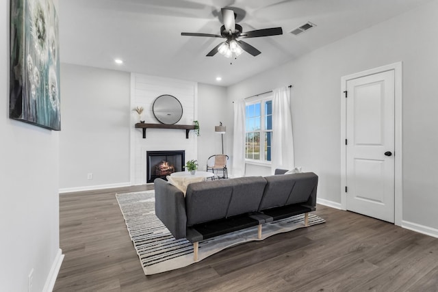 living area with a large fireplace, baseboards, visible vents, and wood finished floors