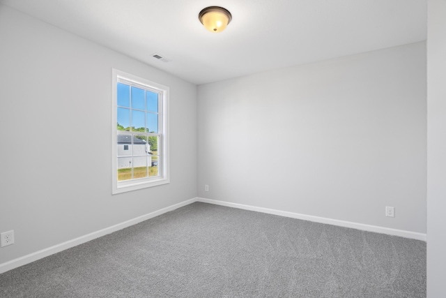 spare room with carpet, visible vents, and baseboards