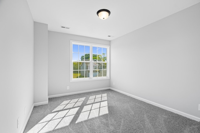 empty room featuring carpet flooring, visible vents, and baseboards