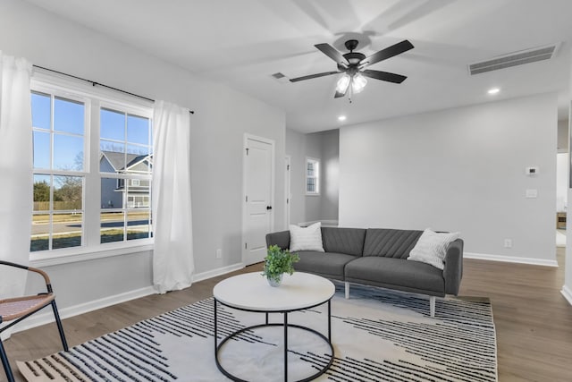 living room featuring wood finished floors, visible vents, and baseboards