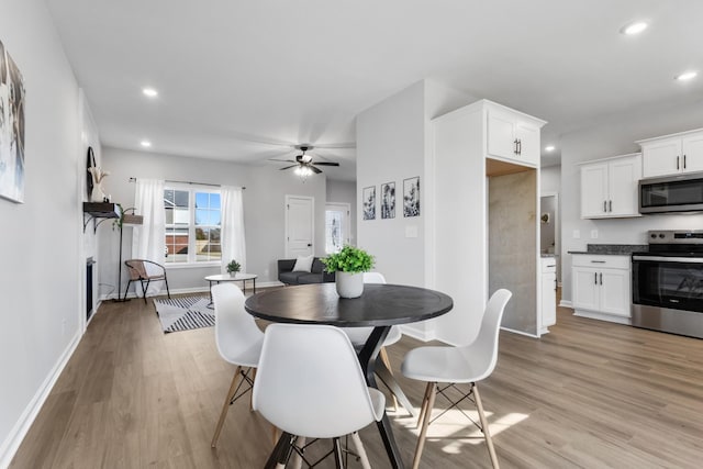 dining area with light wood finished floors, baseboards, ceiling fan, a fireplace, and recessed lighting