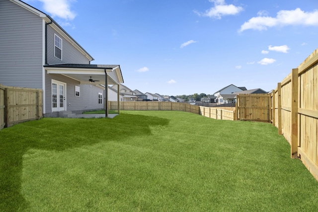 view of yard with french doors, a ceiling fan, entry steps, a residential view, and a fenced backyard