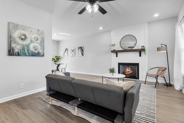 living area featuring a fireplace, baseboards, wood finished floors, and recessed lighting