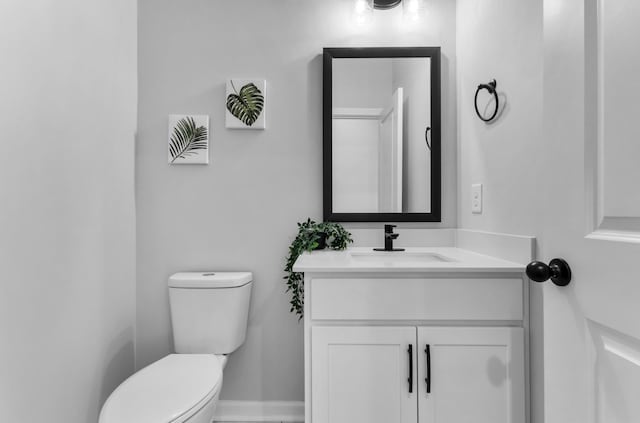 bathroom with toilet, baseboards, and vanity