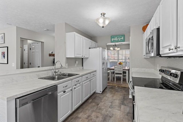 kitchen featuring a textured ceiling, appliances with stainless steel finishes, white cabinets, and a sink