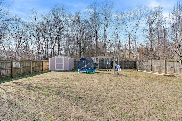 view of yard featuring a trampoline, an outbuilding, a playground, a storage unit, and a fenced backyard