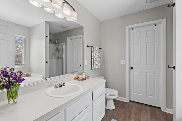 bathroom with visible vents, toilet, wood finished floors, walk in shower, and vanity