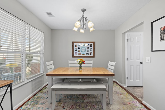 dining area with baseboards, visible vents, and an inviting chandelier